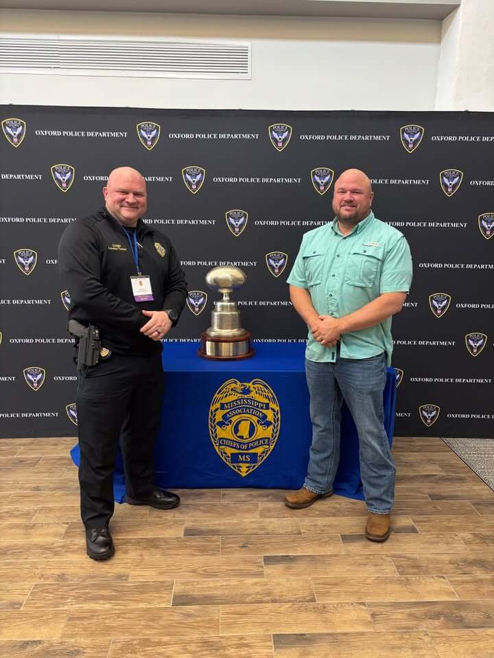 Chief Tucker and Major Moore pose with Mississippi football memorabilia in Oxford